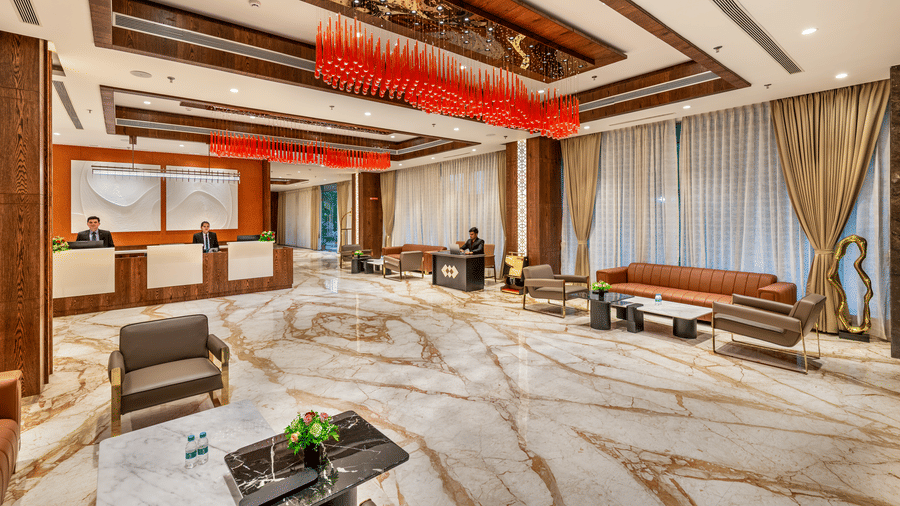 A grand hotel lobby featuring a marble floor, modern seating, and a striking red glass chandelier, with the reception desk in the background - Skkylight Lords Inn, Nanded