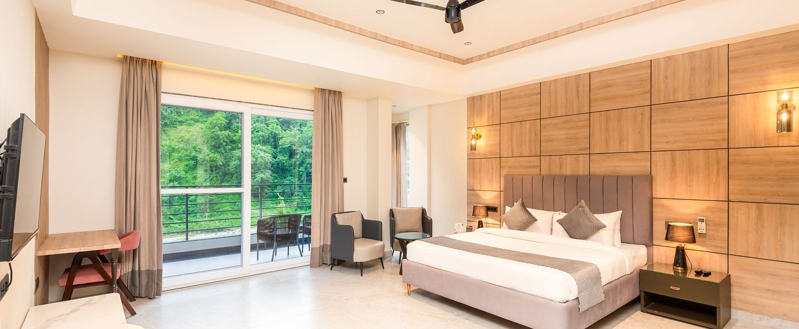 Overview of Premium Room at DLS Divine River Resort and  Spa featuring a  king bed , side table, warm lighting, chair and balcony with forest views.