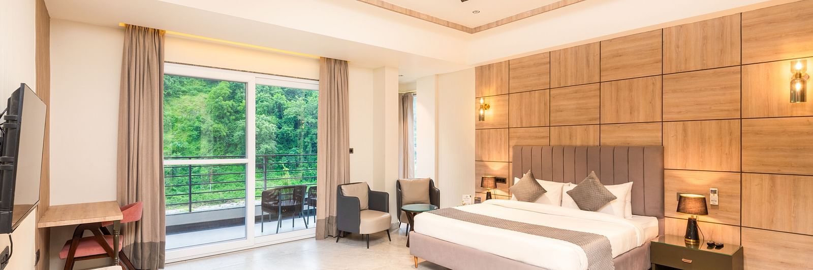 Overview of Premium Room at DLS Divine River Resort and  Spa featuring a  king bed , side table, warm lighting, chair and balcony with forest views.