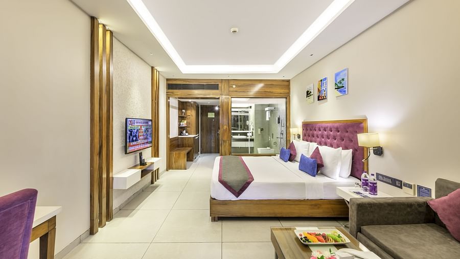 a wide angle shot of a hotel room featuring a double bed, a couch with a coffee table and a work desk - Golden Tulip, Candolim, Goa