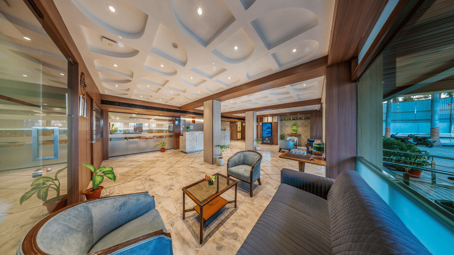A hotel lobby area of Lords Eco Inn with modern, curved sofas and a wooden ceiling design