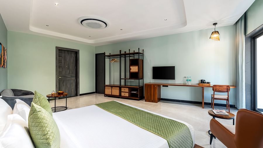 Club Suite with Valley View Sitout furnished with a king size bed, a television, and wooden furniture, presenting a comfortable and stylish interior at The Qualia Resort Club & Brewery, Udaipur.