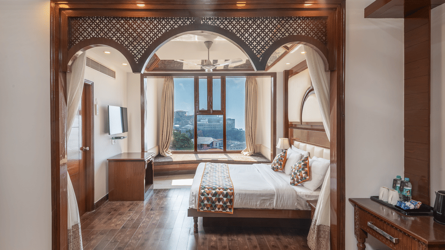 Luxurious suite with elegant wooden arches, plush bed, and large windows at The Solitaire Resort, blending classic charm with modern comfort for a refined stay.