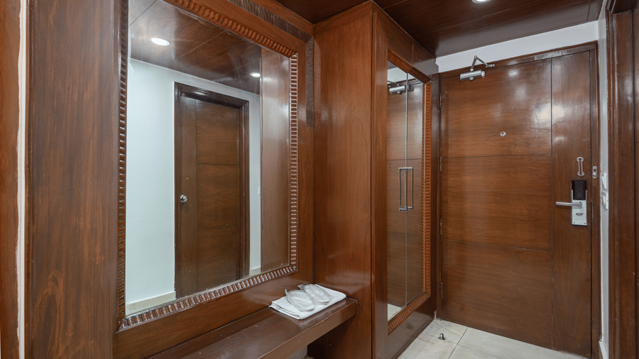 Wooden wardrobe and mirror unit with luggage space beside the entrance at The Solitaire Resort, offering practical storage solutions and stylish interior details.