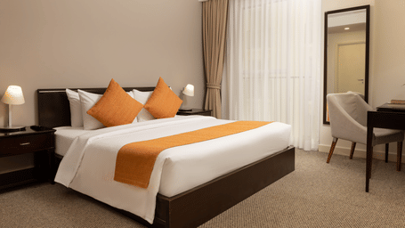 Three Bedroom Family Suite bedroom at Central Mansions, Phnom Penh featuring a king bed, bedside tables, and a work desk.