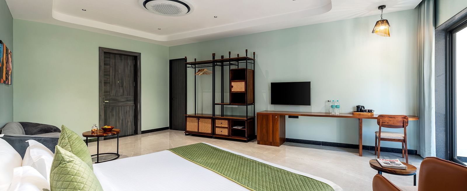 Club Suite with Valley View Sitout furnished with a king size bed, a television, and wooden furniture, presenting a comfortable and stylish interior at The Qualia Resort Club & Brewery, Udaipur.