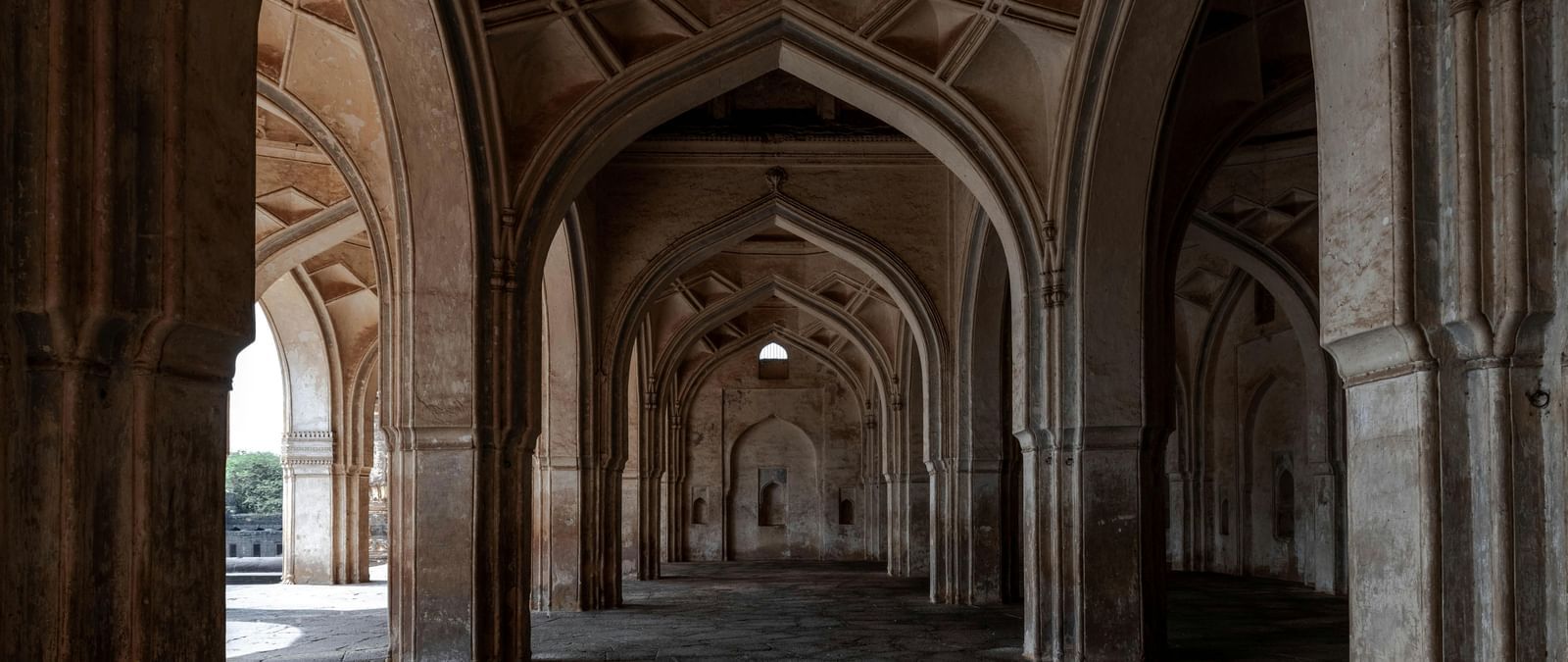 Stone arches and pillars forming a covered passage inside a historic monument.