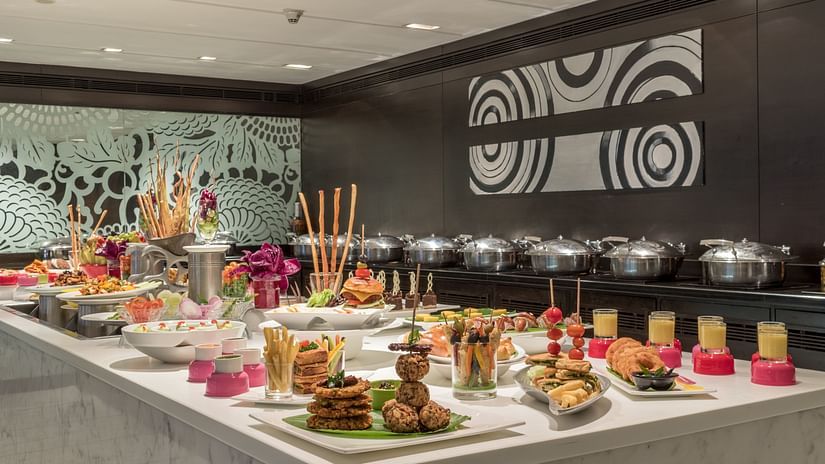 Lavish buffet setup with various plated dishes, desserts, and decorative elements in a restaurant setting.