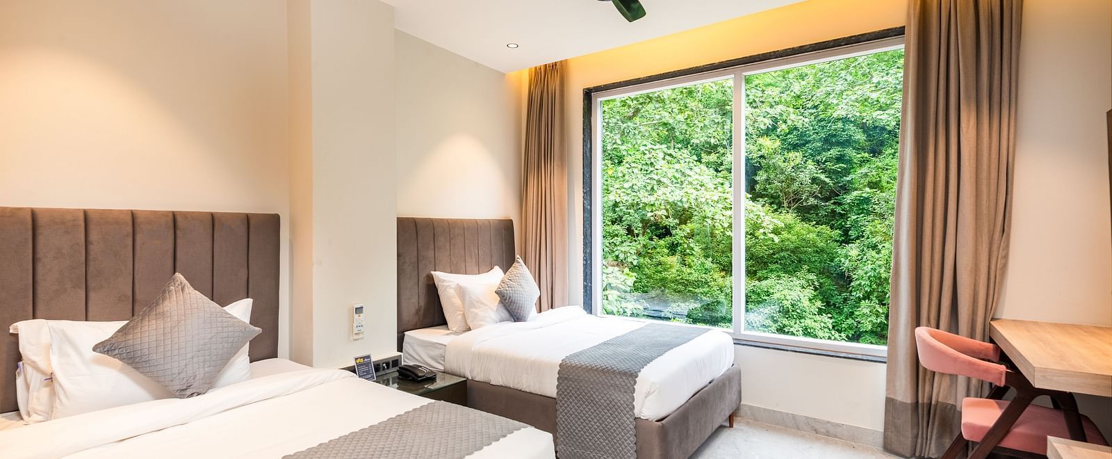Deluxe Room at DLS Divine River Resort and  Spa featuring a two king bed , side table, warm lighting and a balcony with forest views.