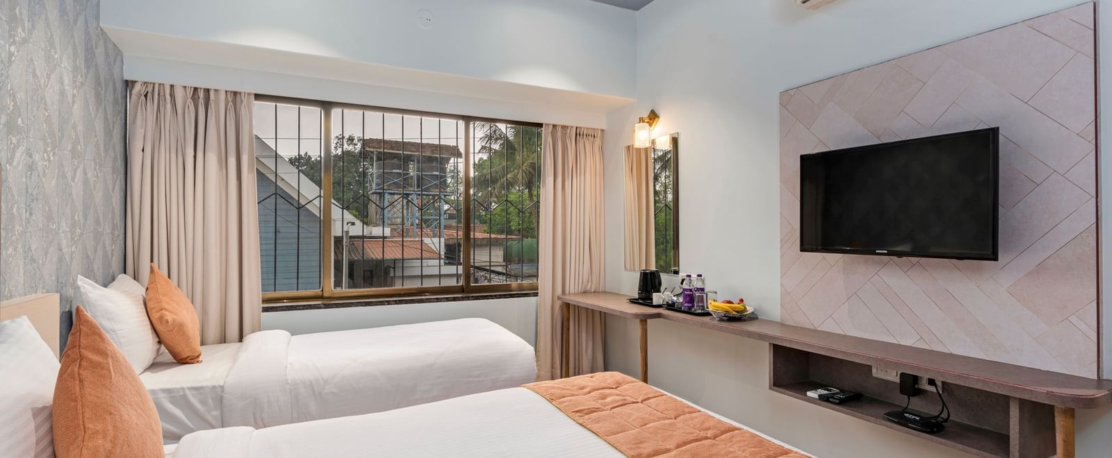 Bright, airy room at Emerald Retreat, Tungarli with a double bed & a single bed, a TV unit, and pastel-themed decor for a restful stay.