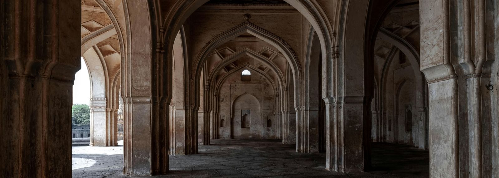 Stone arches and pillars forming a covered passage inside a historic monument.
