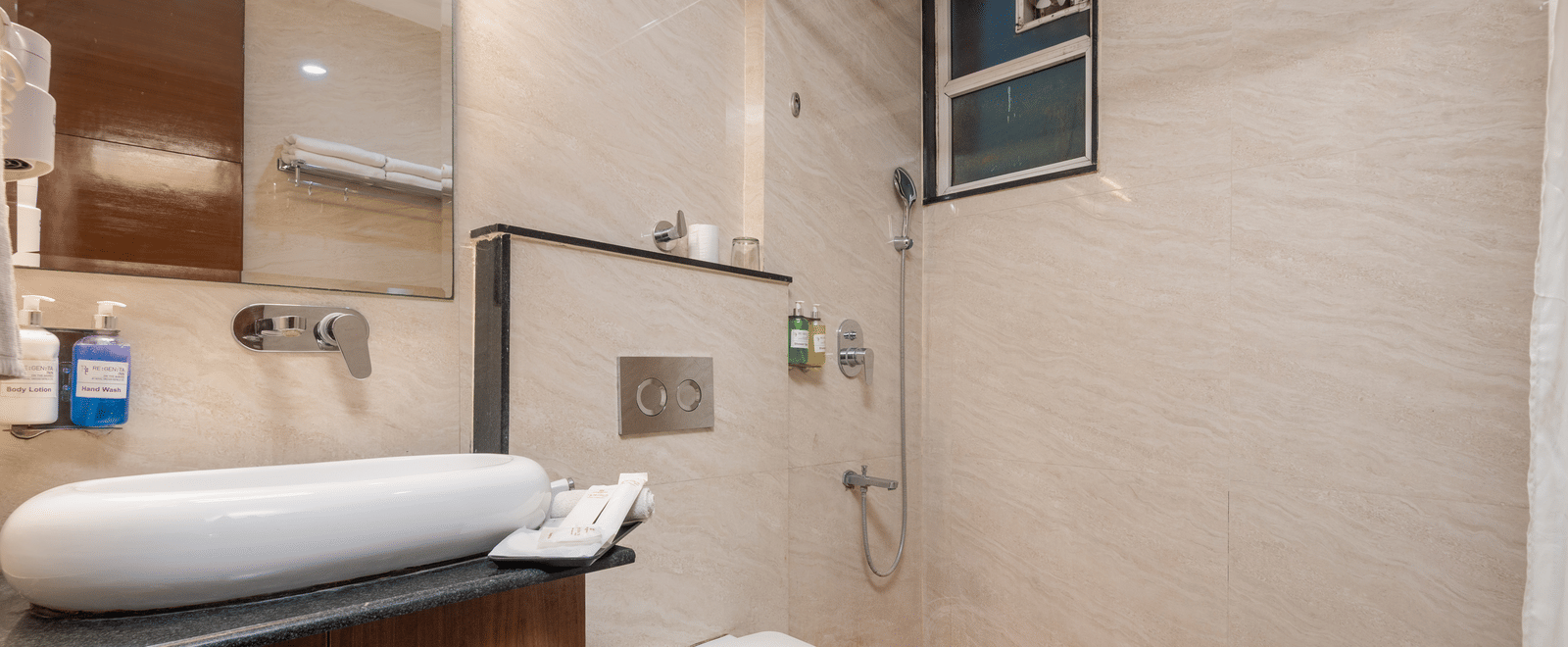 Bathroom with shower, toilet, and grab bar at DLS Hotels On The Ganges.