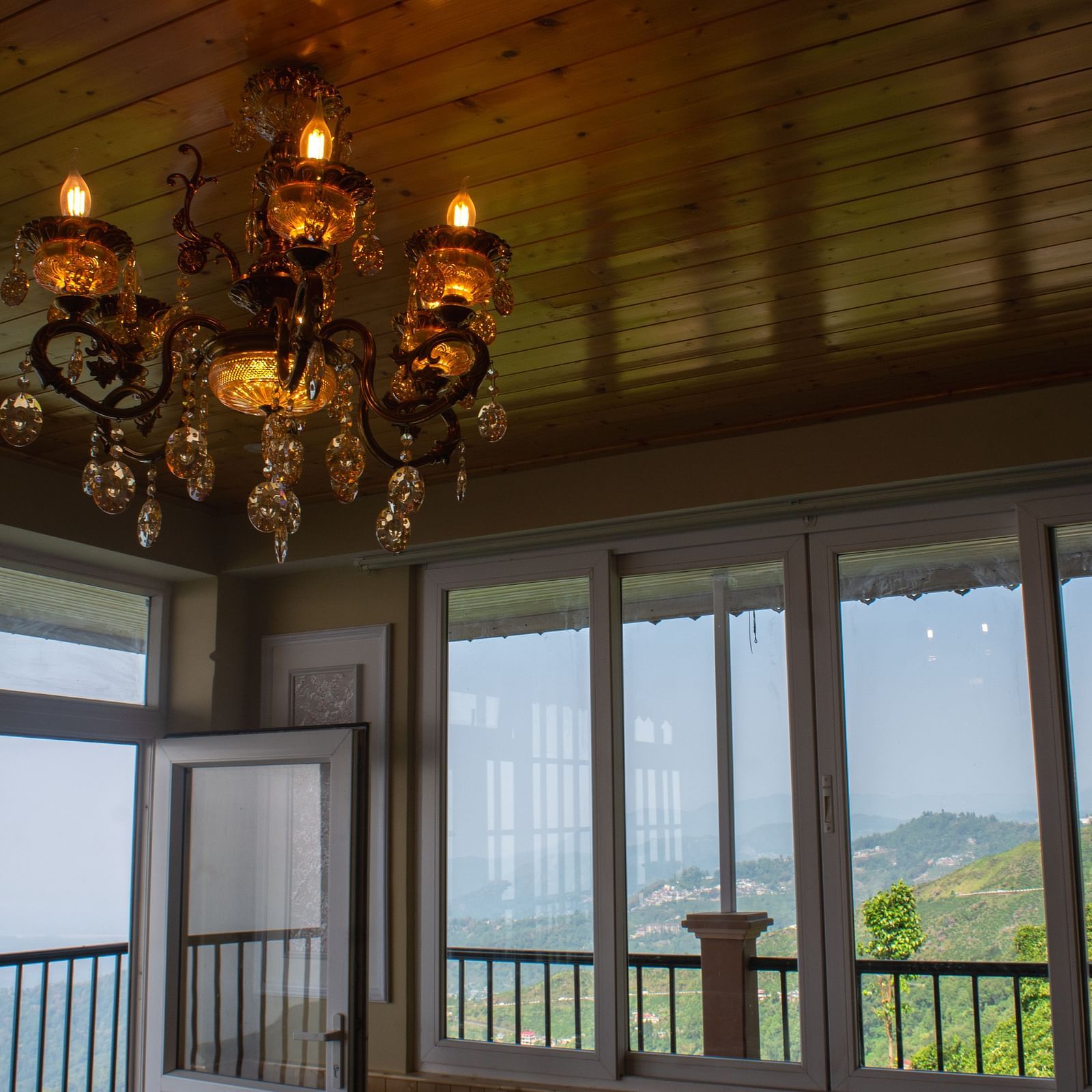 An imaging of a room with a chandelier hanging over viewing the mountains  - Avianna Windy House Wellness Retreat & Spa