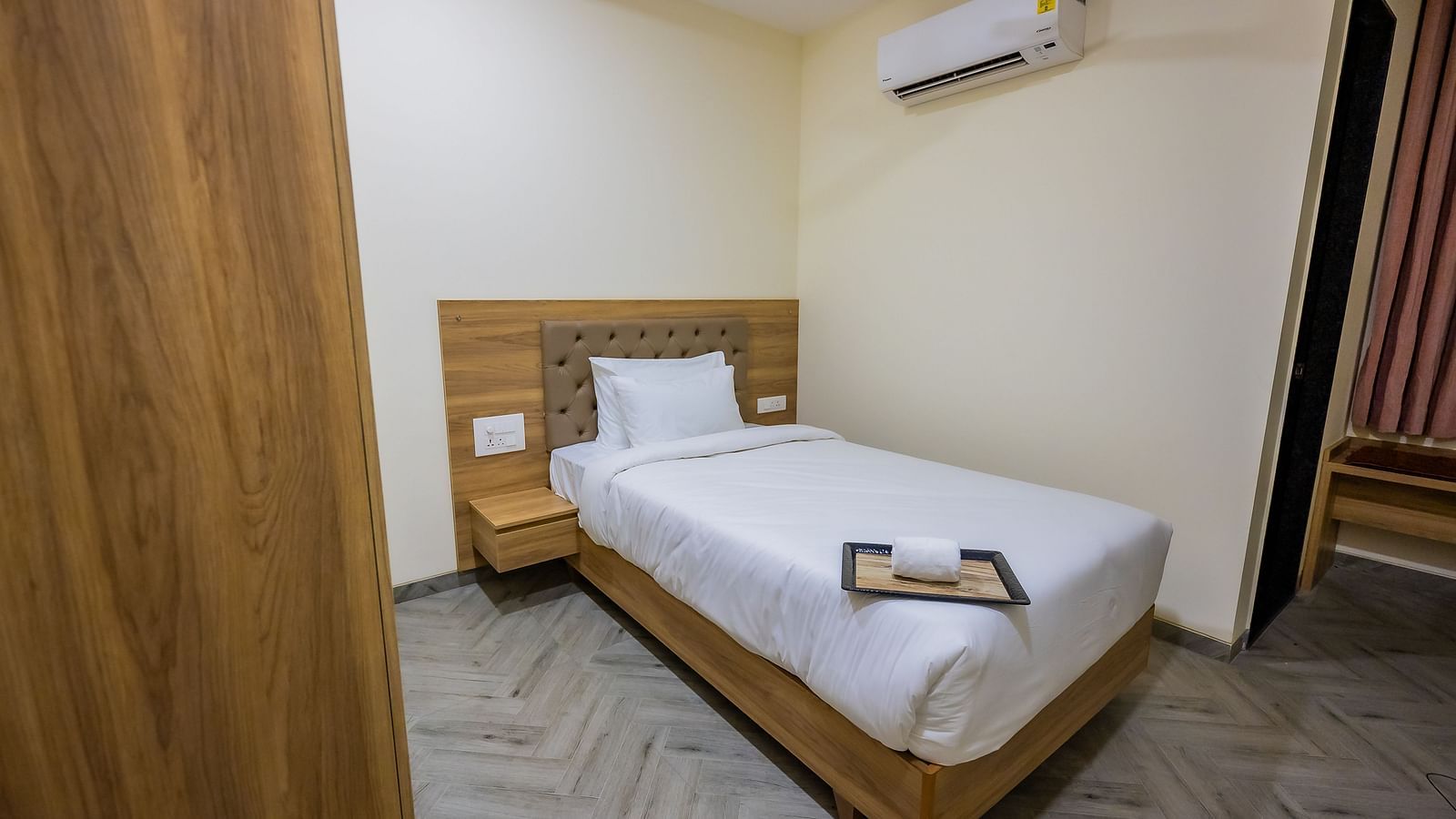 A hotel room, showcasing the bed and comfortable surroundings with the added detail of the air-conditioning unit.
