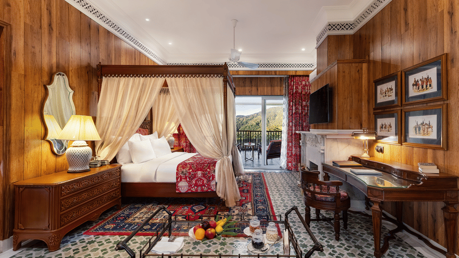 Spacious wooden-panelled suite with four-poster bed and writing desk at Mayfair Manor, Jungpana.
