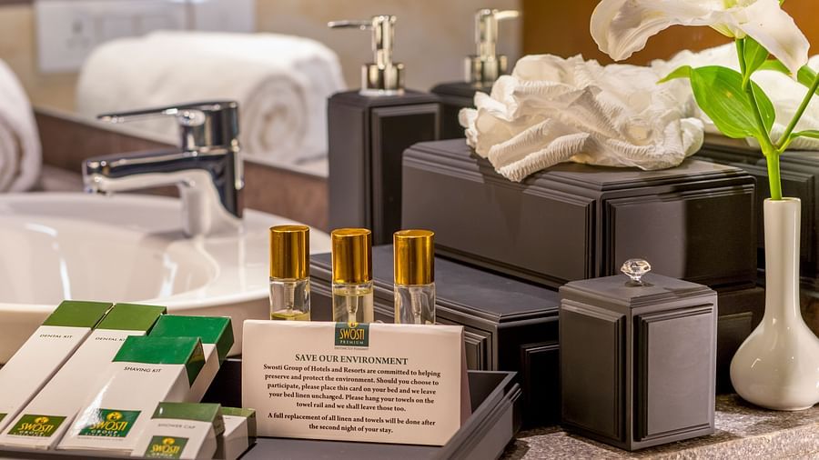 Various toiletries and towels neatly arranged near the washbasin, accompanied by a vase with decorative flowers.