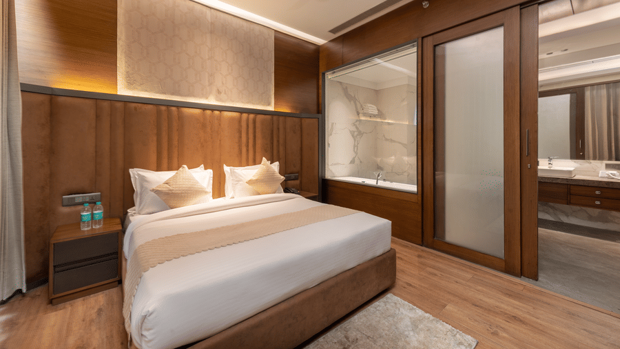 A room with a king size bed, side tables, sliding doors, and ceiling fans, indoors at DLS Hotels Amritsar.