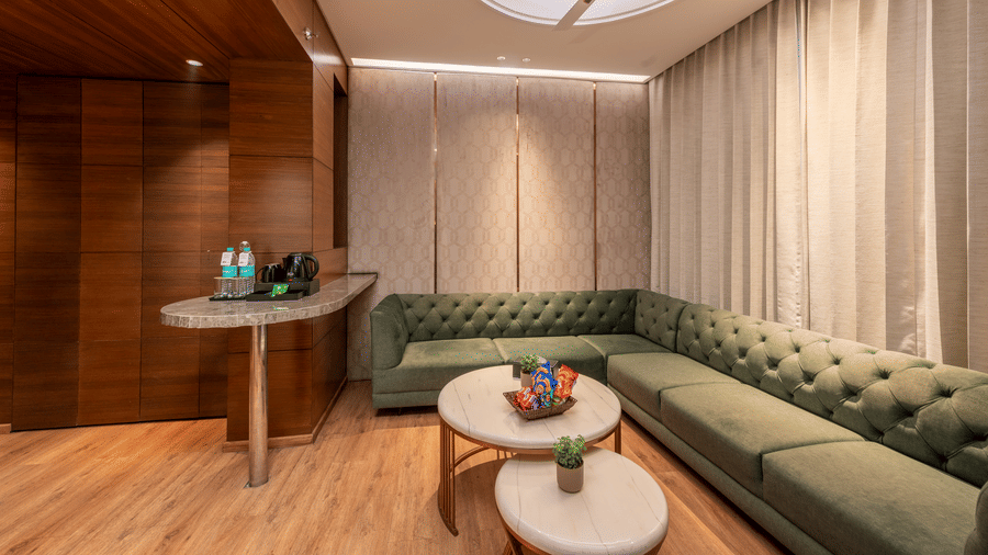 A seating area with a sofa, table, curtains, and a table inside the room at DLS Hotels Amritsar.