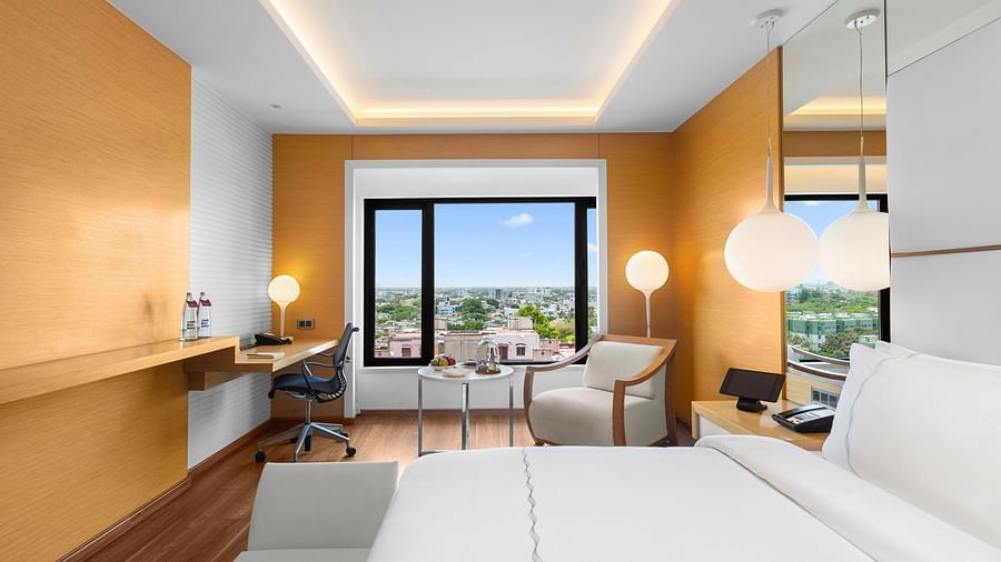 Side view of Club Room with a spacious cozy bed, corner chair, and a view from the window at The Residency Towers Coimbatore