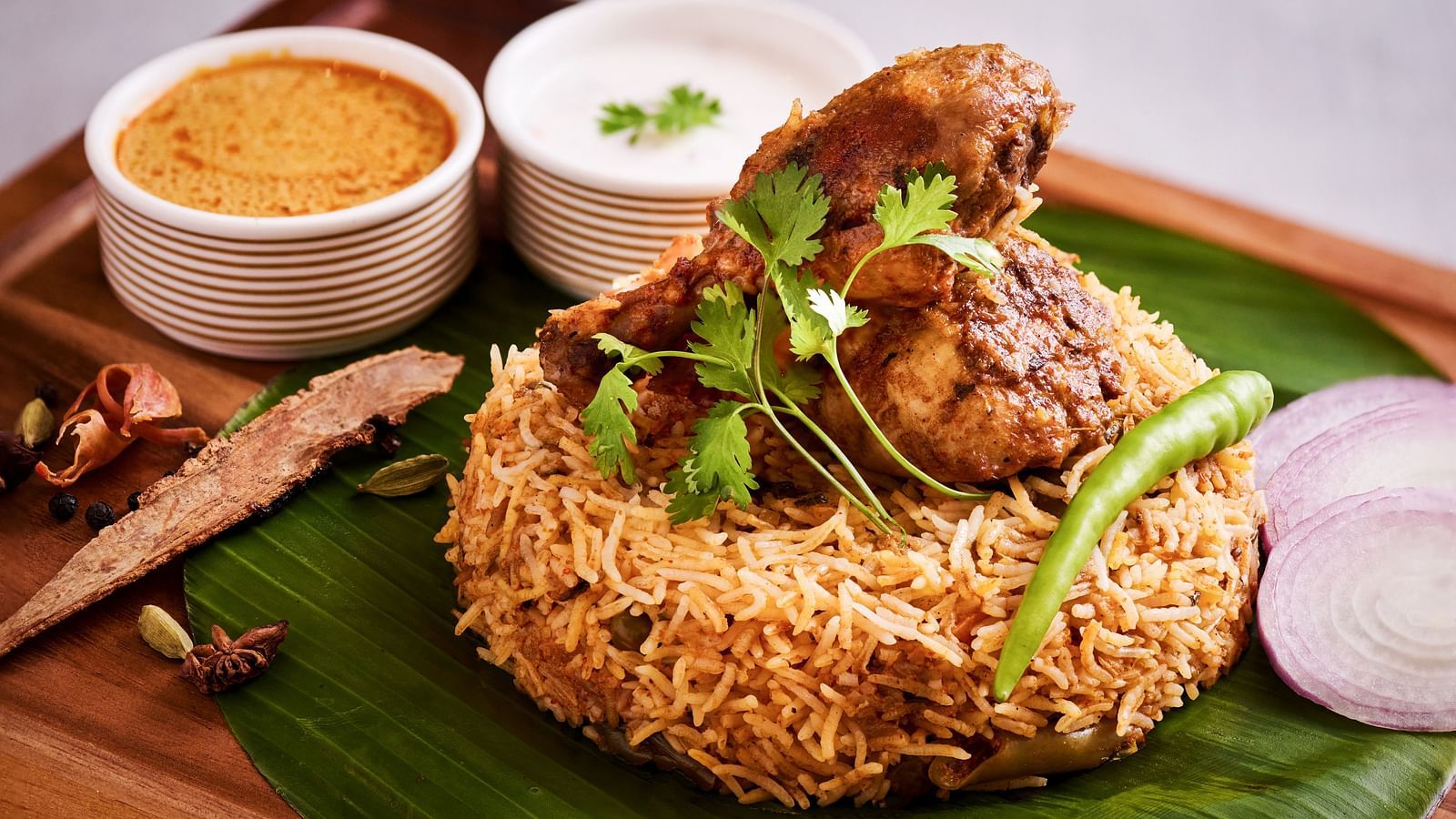 Biryani served on a leaf with curries placed alongside each other.