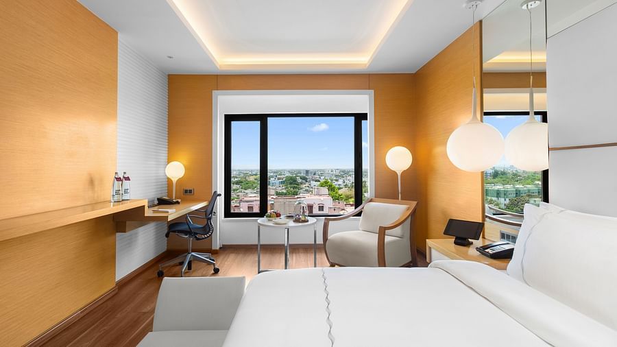 Side view of Club Room with a spacious cozy bed, corner chair, and a view from the window at The Residency Towers Coimbatore