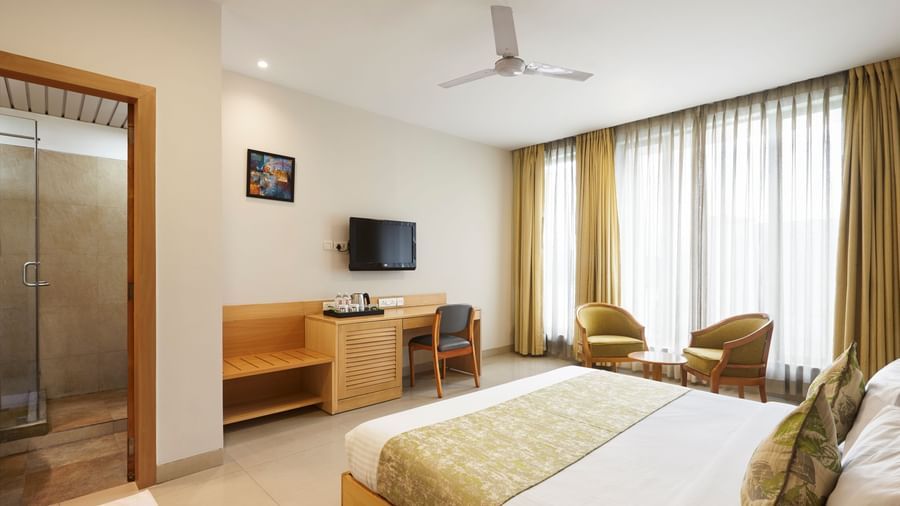 A clean hotel room at Monday Hotels Mahape, Navi Mumbai, with a comfortable bed and two chairs by the window.