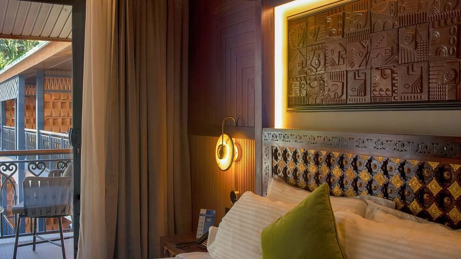 Coral Teal Suite at Coral Reef Resort and Spa in Havelock featuring a plush bed with a warm light over the nightstand next to it and a glimpse of the balcony on the side