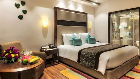 Serene Room with king size bed, table and wall art at Grand Chennai By GRT Hotels.