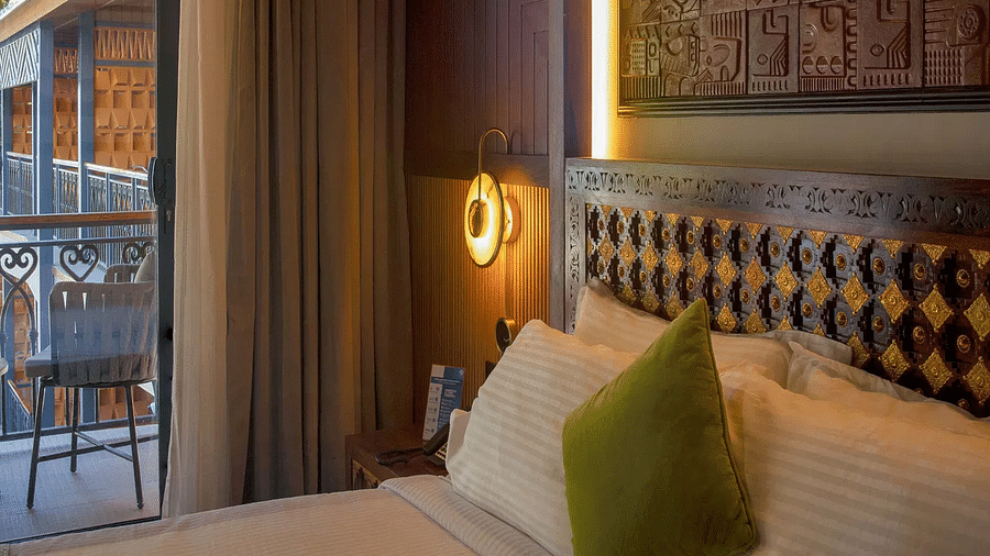 Coral Teal Suite at Coral Reef Resort and Spa in Havelock featuring a plush bed with a warm light over the nightstand next to it and a glimpse of the balcony on the side