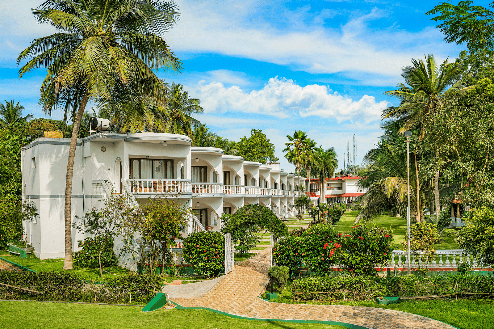 A facade image of a hotel building surrounded by lush greenery
