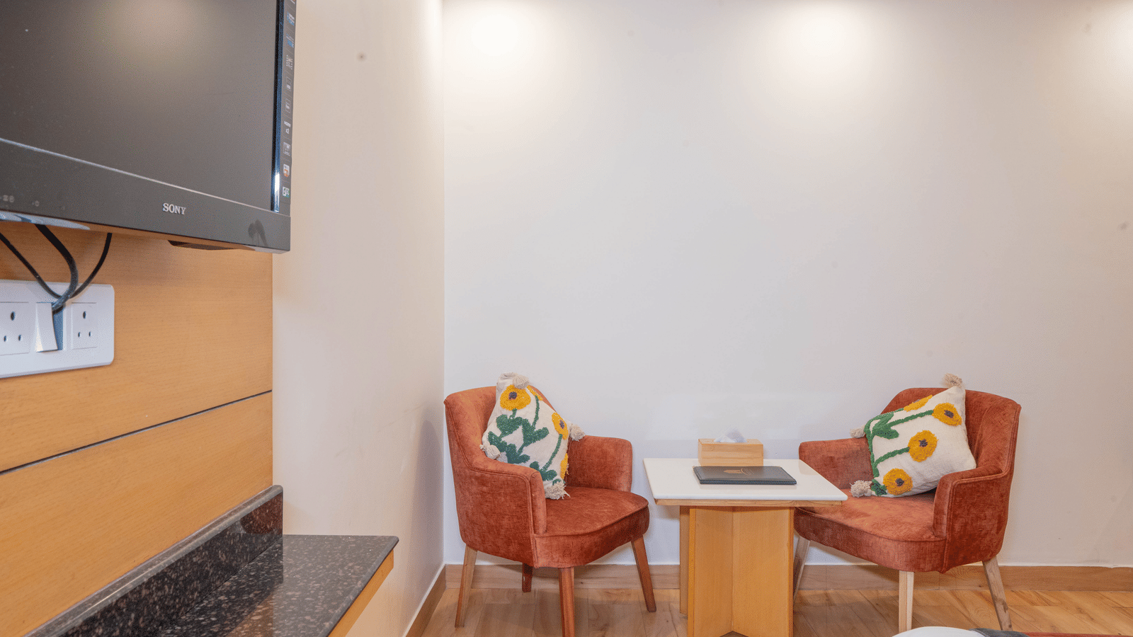 A sitting area with chairs and table near television at Perfectstayz Premium at Mall Road Hotel Super, Mussoorie.