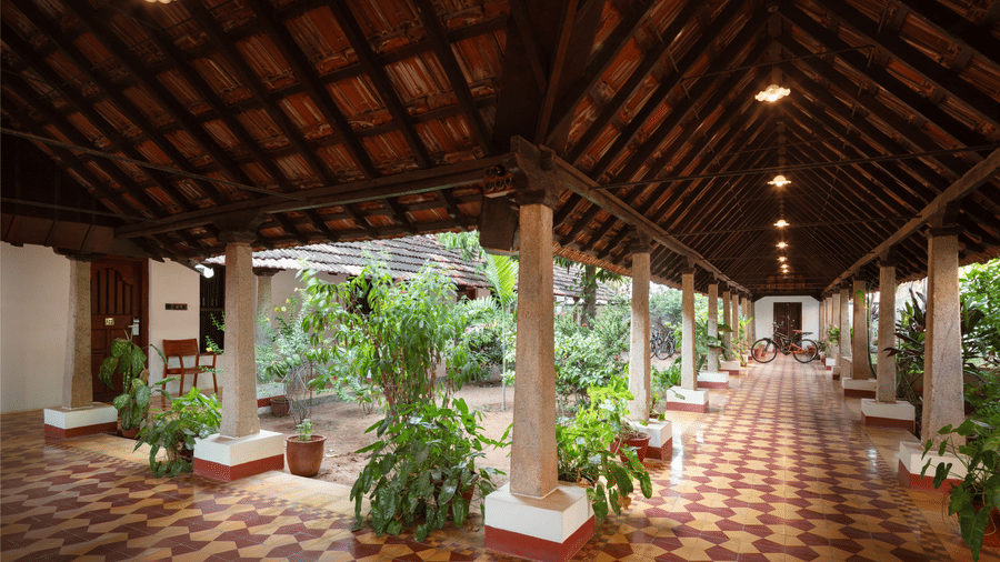 Traditional Indian courtyard at Chidambara Vilas Resort, featuring decorative floor rangolis and a distinctive wooden overhead structure - Chettinad Resort Contact