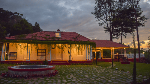 A cottage in the midst of a lawn overlooking the grey sky - Ibex Resort, Coonoor (Leewood).