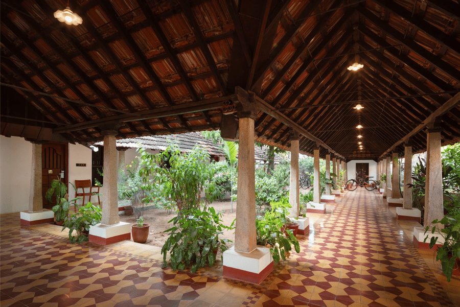 Traditional Indian courtyard at Chidambara Vilas Resort, featuring decorative floor rangolis and a distinctive wooden overhead structure - Chettinad Resort Contact