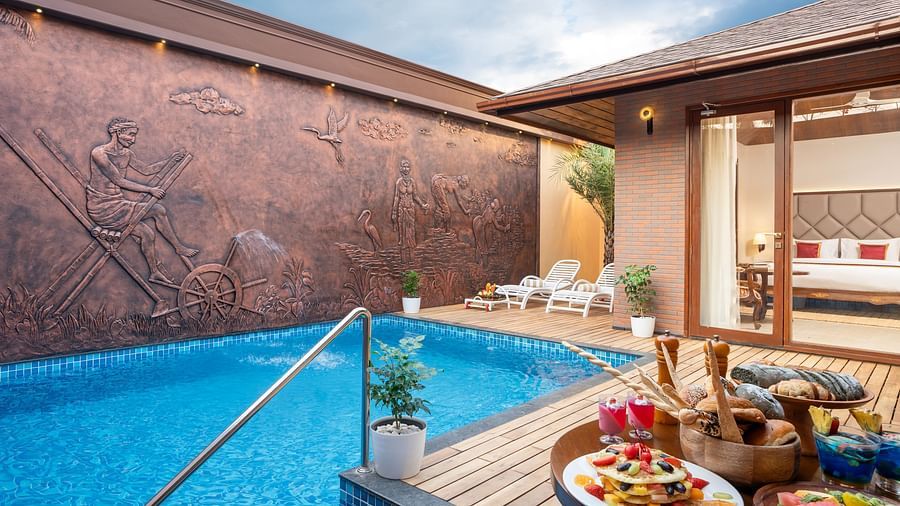 Pool Villa at Uday Backwater Resort featuring a swimming pool with food served on a table at the pool deck and a couple of lounge seaters on the other side of the deck