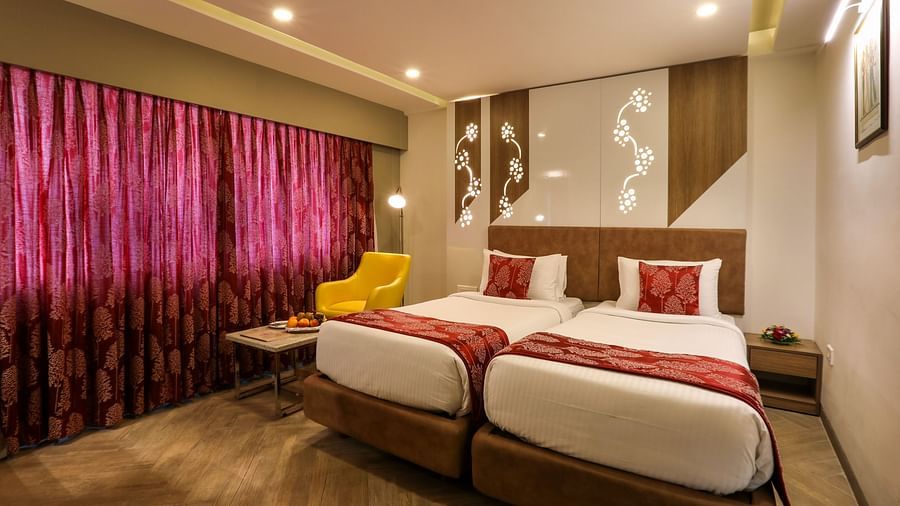A bedroom with two single beds and a sofa and small table on one end beside the windows - Mango Hill Central, Chennai