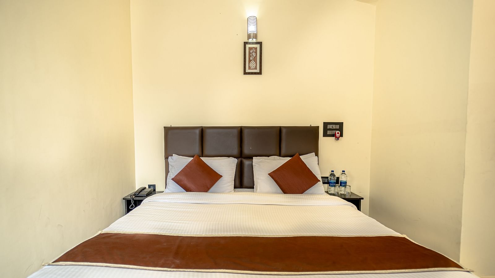 a room at Flutter Hotels & Resorts featuring a bed and brown pillows