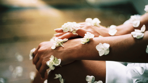 hands with glowing skin and flower petals falling on them