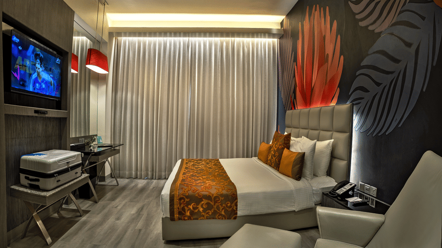 Suite at The Sonnet, Kolkata featuring double bed, bedside tables, a television and lounge chair.