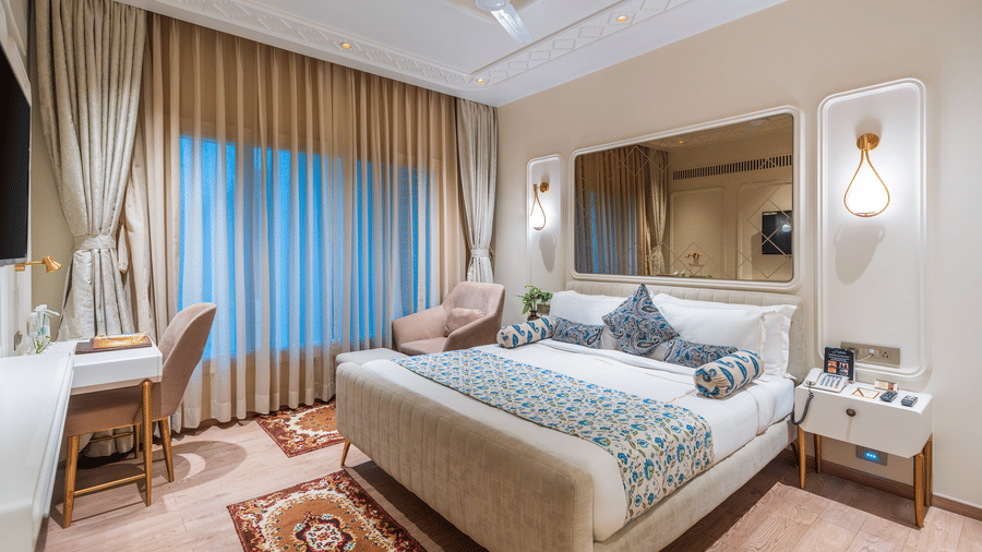 Full view of the beautiful Premium Room with the double bed at the centre, featuring a wide mirror above the headboard - Amantra Comfort Hotel
