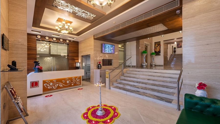 The brightly lit lobby of Dwarkadhish Lords Eco Inn featuring a reception desk, seating area, and decorative rangoli on the floor.