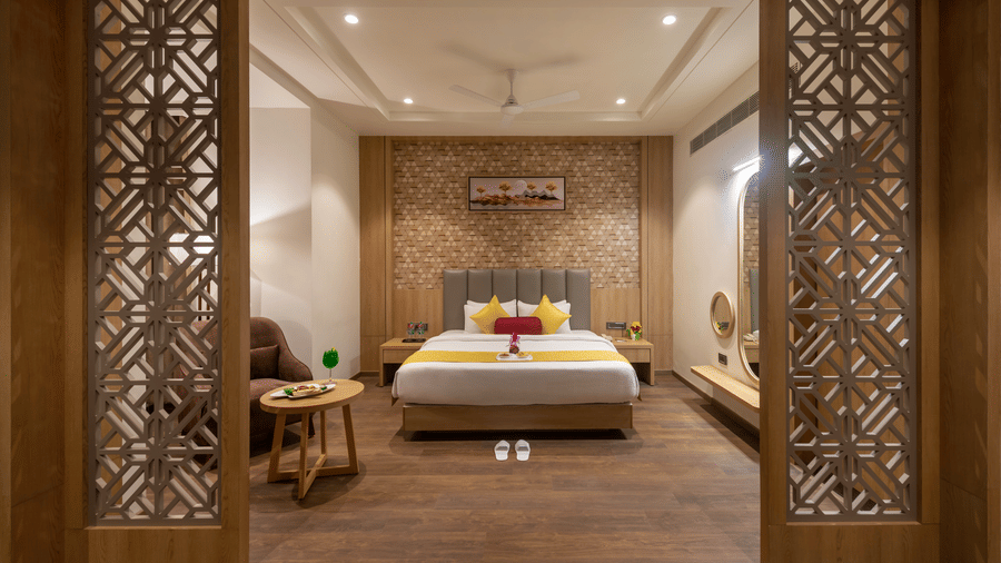 Spacious and elegantly designed a suite at Lords Inn Somnath, featuring a king-size bed with plush pillows, modern decor, and a table set with refreshments.