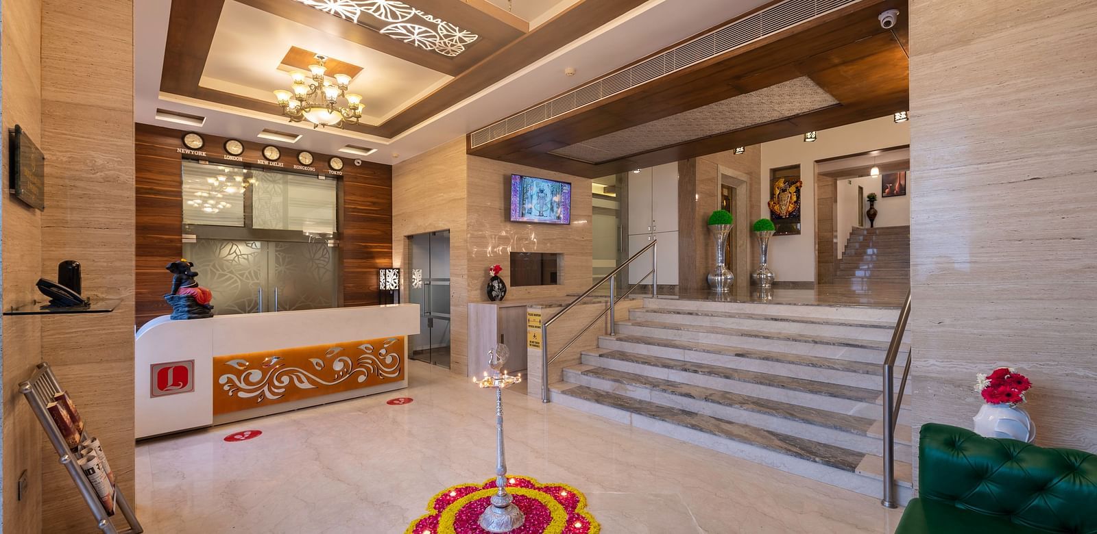 The brightly lit lobby of Dwarkadhish Lords Eco Inn featuring a reception desk, seating area, and decorative rangoli on the floor.