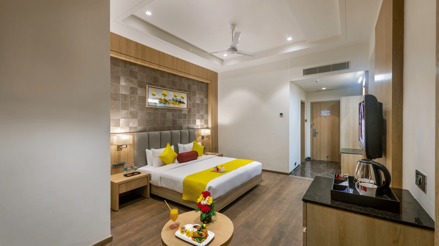 A premium room in Lords Inn Somnath with modern interiors, featuring a neatly made double bed, TV and a table set with refreshments.