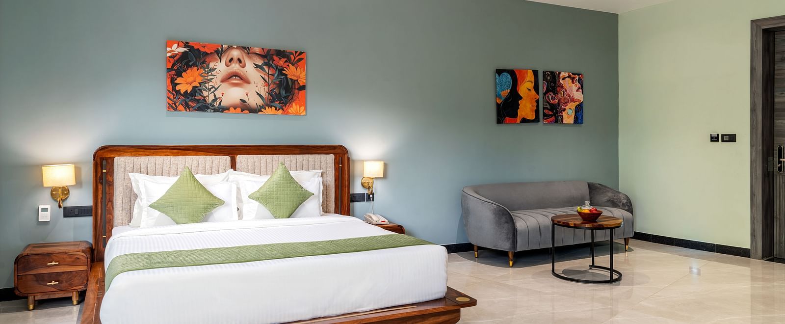 Club Suite with Valley View Sitout displaying a king size bed, a seating area, and artwork on the walls, illuminated by soft lighting at The Qualia Resort Club & Brewery, Udaipur.