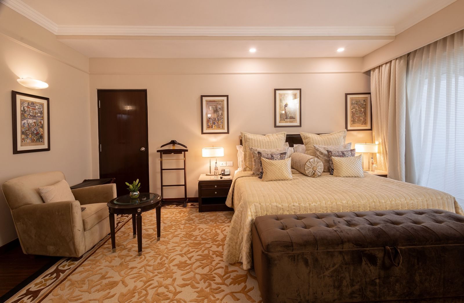 image of the bedroom of the heritage terrace room with plush bedding and a single seater beige coloured couch - image of a spacious and an elegant bedroom of the heritage terrace room - The Claridges New Delhi