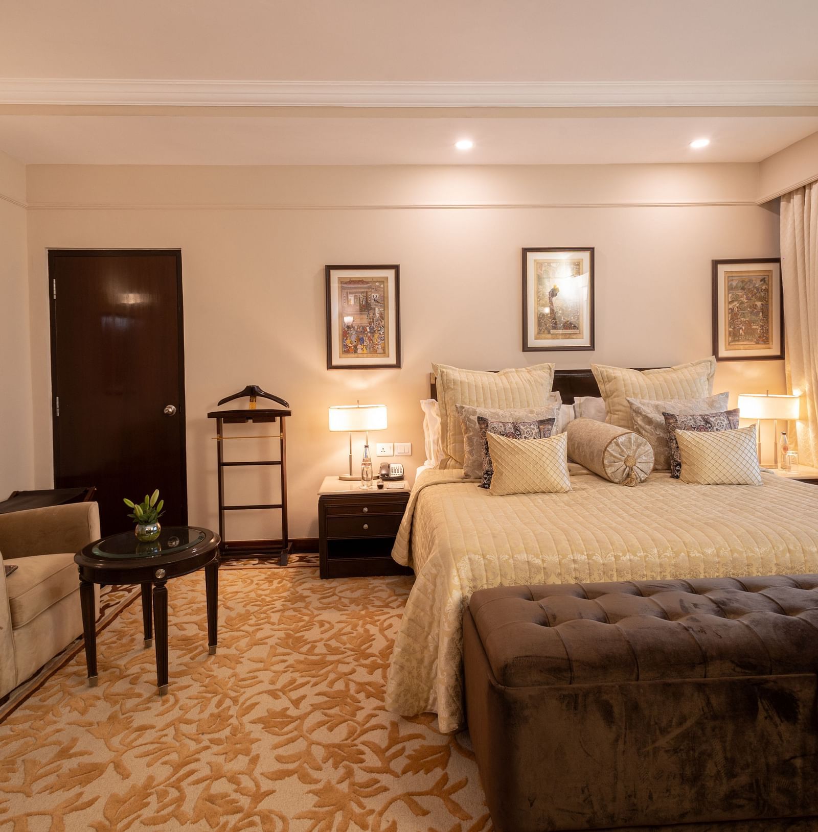 image of the bedroom of the heritage terrace room with plush bedding and a single seater beige coloured couch - image of a spacious and an elegant bedroom of the heritage terrace room - The Claridges New Delhi