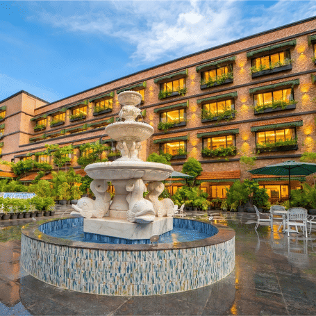 Front view of MAYFAIR Bay Resort, Paradeepfeaturing a grand multi-tier stone fountain and the resort's golden-lit facade.