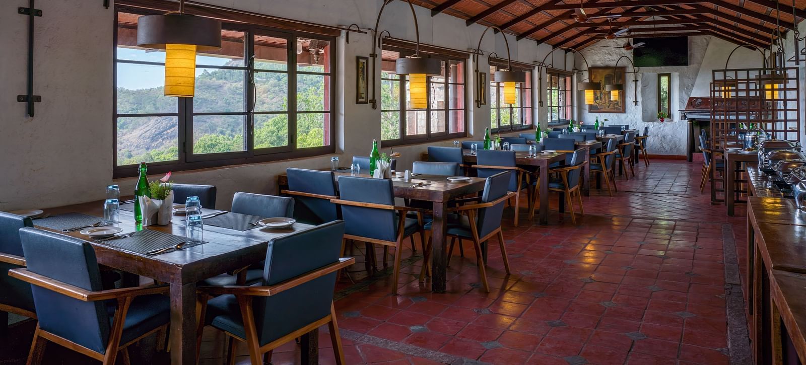 Spacious dining hall with rows of tables and chairs, wooden ceiling, and large windows. | Mango Hill, Yercaud