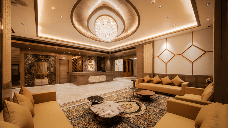 A spacious waiting lounge with plush tan sofas, patterned rugs, and elegant ceiling fixtures at Ananta Express, Katra.